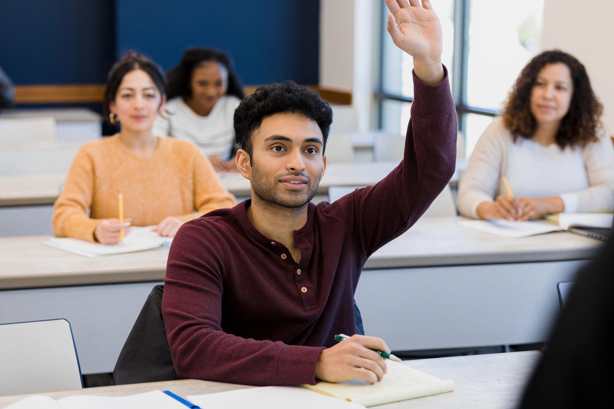 Students in a classroom raising hands